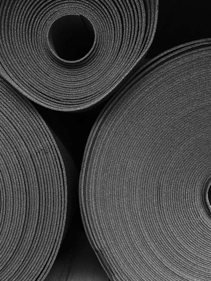 services-02 Monochrome photo of stacked rolled yoga mats, perfect for fitness-focused concepts.
