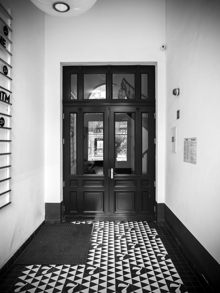 services-img Stylish black and white photo of a classic interior entrance with decorative tiles in Wrocław, Poland.