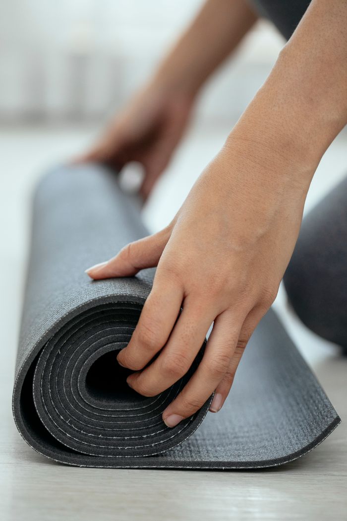 services-02 Closeup of crop anonymous lady holding rolled mat on floor against blurred background